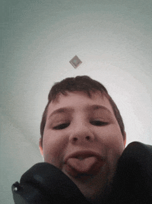 a young boy sticking his tongue out in front of a ceiling light