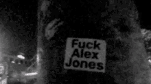 a black and white photo of a sign that says ' fuck alex jones ' on it