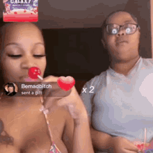 a woman in a bikini is eating a lollipop next to another woman .