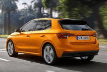 a yellow skoda car is driving down a road