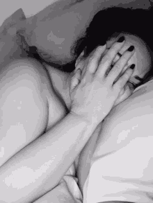 a black and white photo of a woman covering her face with a man 's hand