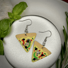 a pair of earrings in the shape of slices of pizza