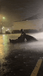 a man in a batman costume is laying in the rain