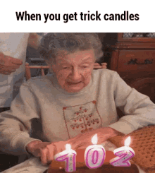 an elderly woman is blowing out candles on a cake with the words when you get trick candles below her