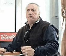 a man is sitting at a table with a plate of food in front of a coca cola sign