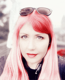 a woman with pink hair is wearing sunglasses and a black shirt