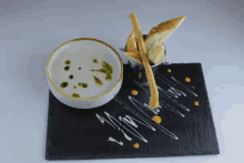 a bowl of soup and bread on a black plate