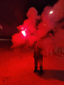 a man stands in the snow holding a red flare