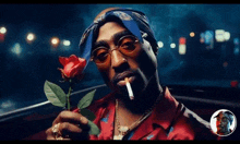 2pac is smoking a cigarette and holding a rose in his hand .