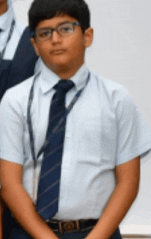 a young boy wearing glasses and a tie is standing in front of a white wall