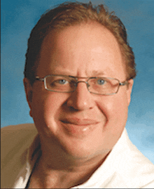 a man wearing glasses and a white shirt smiles at the camera