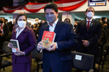 a man wearing a mask holds up a book called el diario presidente