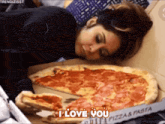 a woman is laying on a bed eating a large pizza and saying i love you