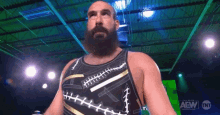 a wrestler with a beard is wearing a black and gold tank top with stitches on it .