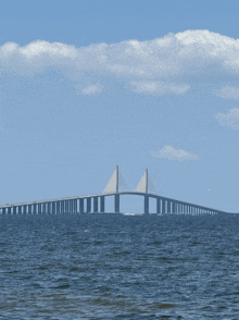 a bridge over a body of water with a blue sky and clouds