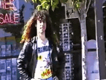 a man with long hair is standing in front of a store with a sign that says sale on it .