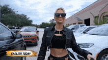 a woman wearing sunglasses and a black jacket is standing in front of a jeep and a sign that says earlier today