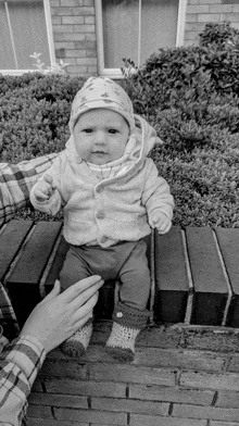 a black and white photo of a baby wearing a hat and socks