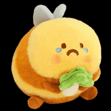 a stuffed bee with a sad face holding a lettuce