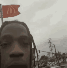 a man with dreadlocks is standing next to a mcdonald 's flag .