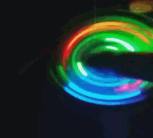 a person 's finger is spinning a green and red lighted object