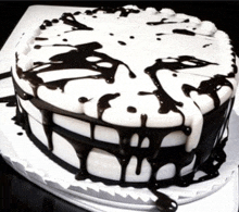 a black and white cake with chocolate dripping down the sides