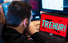 a man sitting in front of a laptop that says trehur on the screen