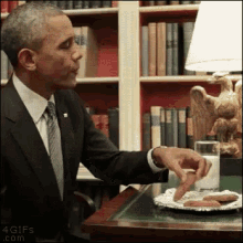 a man in a suit and tie is sitting at a table with a plate of sausages and a glass of milk