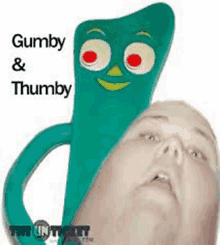 a man is holding a green gumby and thumby toy in front of his face .