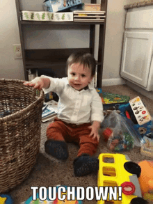 a baby is sitting on the floor with a basket full of toys and the words touchdown on the bottom