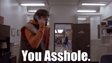a man talking on a phone with the words " you asshole " below him