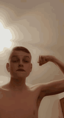 a shirtless young man flexes his muscles in a room