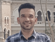 a man with a beard is smiling for the camera in front of a building .