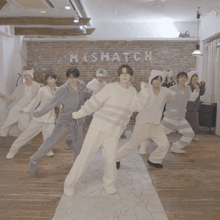 a group of men in pajamas are dancing in front of a wall that says mishmatch