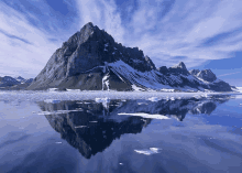 a mountain reflected in a body of water with ice