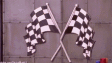 two black and white checkered flags are crossed in front of a wall .