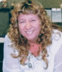 a woman with curly hair is smiling for the camera while wearing a white shirt .