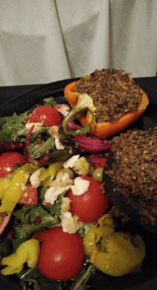 a plate of stuffed peppers and a salad with tomatoes and olives