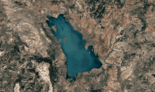 an aerial view of a lake surrounded by mountains and rocks