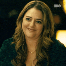 a woman in a green shirt is smiling for the camera with the hbo logo in the background