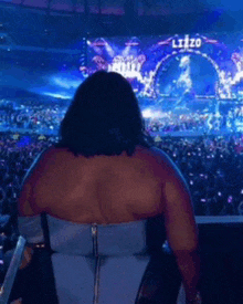 a woman sitting in front of a large screen that says lizzo on it