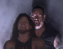 two wrestlers are standing next to each other in a dark room with smoke coming out of their mouths