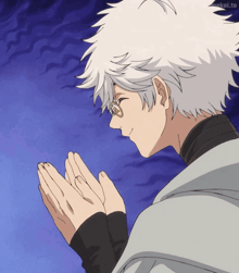 a man with white hair and glasses holds his hands together in prayer