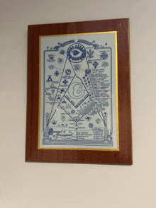 a framed picture of a masonic symbol on a wall with the letters g and g on it