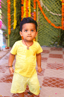 a little boy in a yellow shirt and shorts