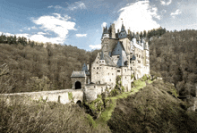 a large stone castle sits on top of a hill in the middle of a forest