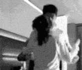 a black and white photo of a man and a woman hugging each other .