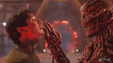 a man is touching a monster 's face with a netflix logo in the corner