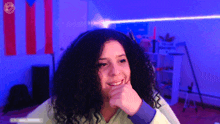 a girl with curly hair is wearing headphones and smiling in front of a blue light