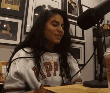 a woman sitting in front of a microphone wearing a kappa shirt